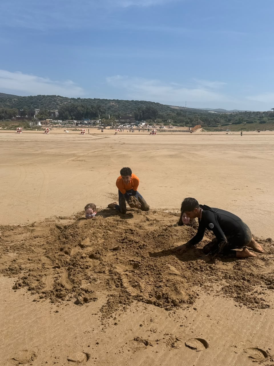 Friends buried in the sand, laughing